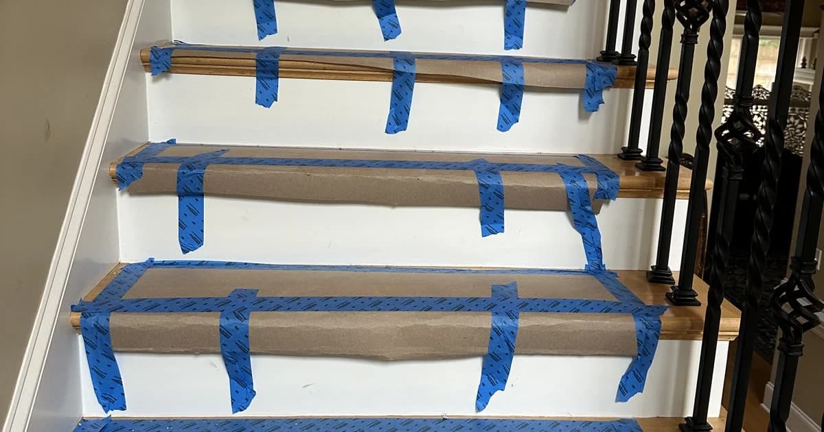 A staircase covered tread by tread with protective paper and tape before work begins.