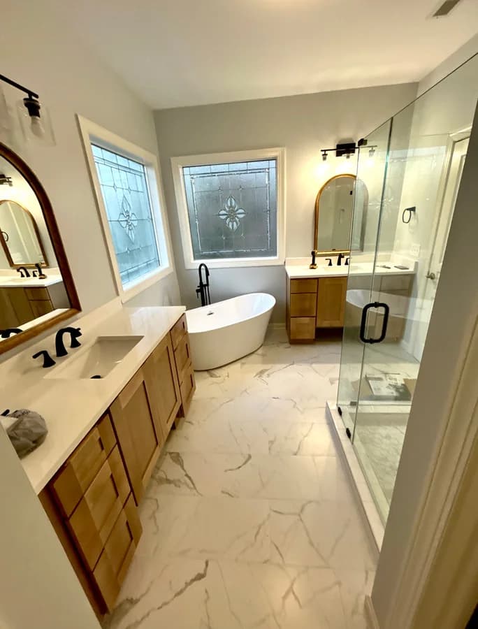 Wide view: the vanity run, the freestanding tub between stained-glass windows and the glass shower.