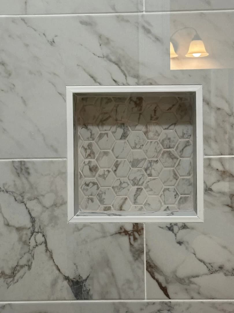 Recessed shower niche with coordinating hex-pattern accent tile and white trim