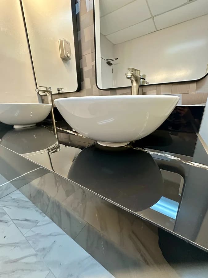 Close view of a vessel basin and its tall brushed-nickel faucet on the polished black counter.